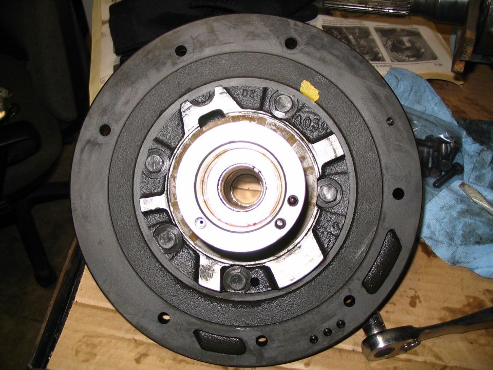 Transmission bellhousing face-up on workbench with ratchet and loose bolts