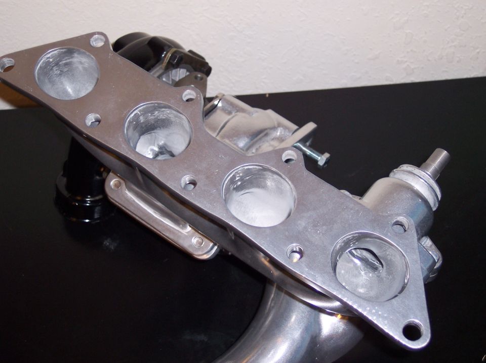 Aluminum intake manifold with four ported runners on a black surface