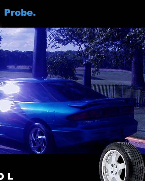 1994 Ford Probe - A blue coupe with a spoiler is parked outdoors, with trees and a fence in the background.