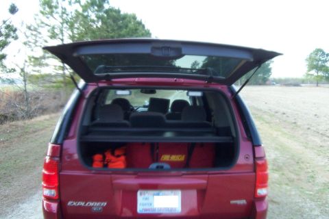 2005 Ford Explorer - Rear view of a red 2005 Ford Explorer, showing the open tailgate with "FIRE RESCUE" bags and safety equipment visible inside.