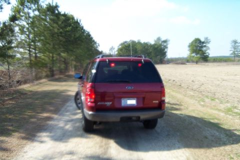 2005 Ford Explorer - The rear view of a red Ford Explorer SUV on a dirt road.