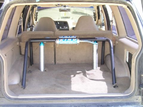 1985 Ford Bronco II - The rear interior of an SUV is shown, a custom roll cage with a prominent King shock absorber.