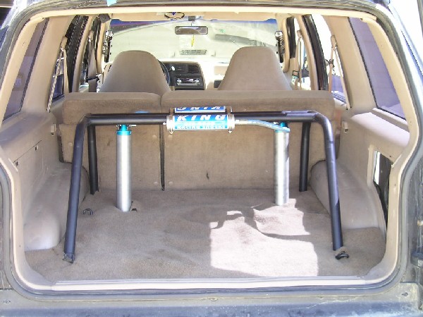 Interior view of an SUV showing a roll cage and two rear seats. A 'KING' shock absorber is mounted on the roll cage