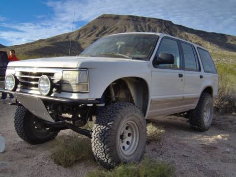 1985 Ford Bronco II - This white SUV, likely a 1990 Ford Explorer, is equipped with large off-road tires and a custom front bumper, suggesting it's built for ter…