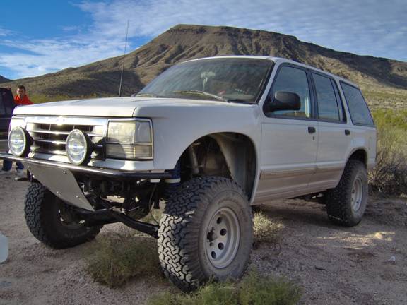 White SUV with off-road tires and custom bumper. Appears to be a 1990 Ford Explorer