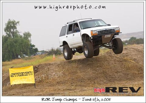 1985 Ford Bronco II - A white SUV performs a jump during an off-road event.