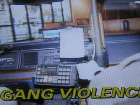 1991 Ford LTD Crown Victoria - photographed television frame showing a police-car dashboard packed with radio equipment, captioned GANG VIOLENCE in yellow.