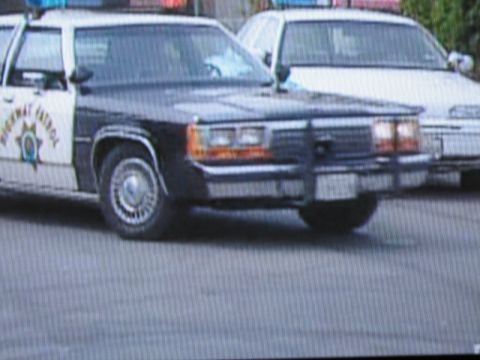 1991 Ford LTD Crown Victoria - photographed television frame of a black-and-white Highway Patrol full-size sedan with star emblem turning on a street.