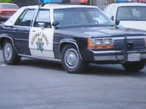 1991 Ford LTD Crown Victoria - photographed television frame showing a black-and-white Highway Patrol full-size sedan with a gold star emblem on the door.
