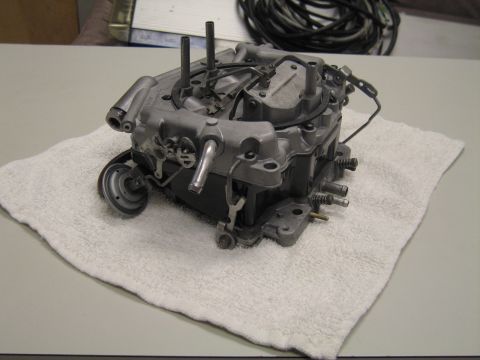 1991 Ford LTD Crown Victoria - four-barrel carburetor shown from a low angle on a white towel, exposing its throttle linkage and base.