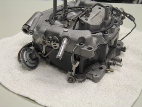 1991 Ford LTD Crown Victoria - Close side view of a four-barrel carburetor on a white towel, showing fuel inlet, linkage and vent tubes.