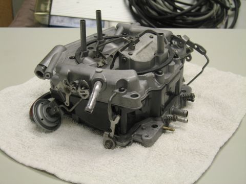 1991 Ford LTD Crown Victoria - four-barrel carburetor rests on a white towel, photographed from the side showing its choke pull-off and linkage.