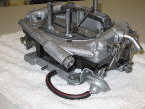 1991 Ford LTD Crown Victoria - base of a four-barrel carburetor on a white towel, displaying throttle plates, linkage and a vacuum diaphragm.