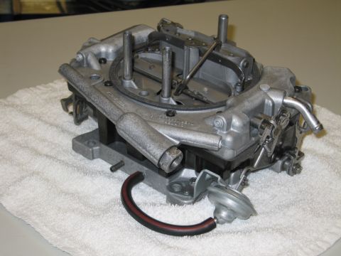 1991 Ford LTD Crown Victoria - four-barrel carburetor seen from its base on a white towel, with venturi bores and a curved vacuum hose.
