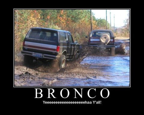 1988 Ford Bronco - Two Ford Broncos navigate a muddy path, splashing water and dirt.