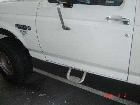 1993 Ford Bronco - Close-up of a white 1993 Ford Bronco's side, the door, step, and tire.