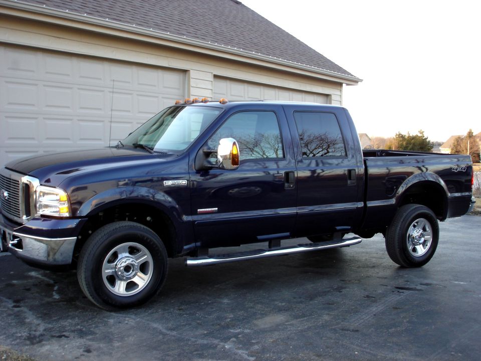 Dark blue Ford F-350 Super Duty pickup truck parked in front of a garage