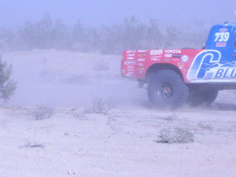 Red number 739 off-road race truck kicking up dust in the desert
