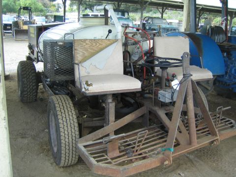 1968 Ford Mustang - A farm implement with a large tank and two seats is parked next to other vehicles.