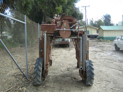 1968 Ford Mustang - Old rusty tractor with large rear wheels, seen from the back. Another vehicle is in the background.