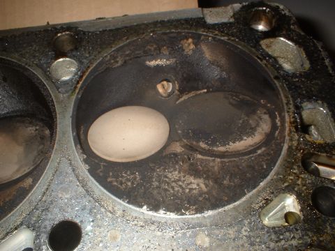 1993 Ford Bronco - Close-up of an engine cylinder head, revealing valve seats and a valve. Carbon deposits are present.