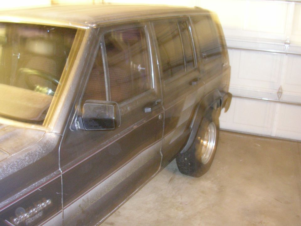 Side view of a 1987 Jeep Cherokee parked in a garage