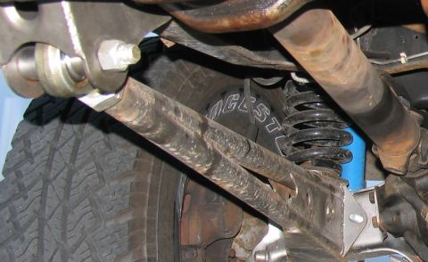 1984 Ford Bronco - Close-up of a vehicle's undercarriage, highlighting suspension parts and a tire with visible branding.