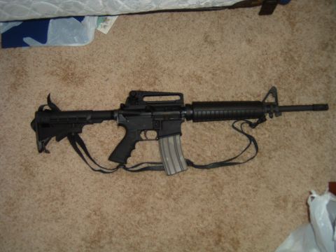 1992 Ford Probe - A black assault rifle with a magazine is shown lying on a carpeted surface.