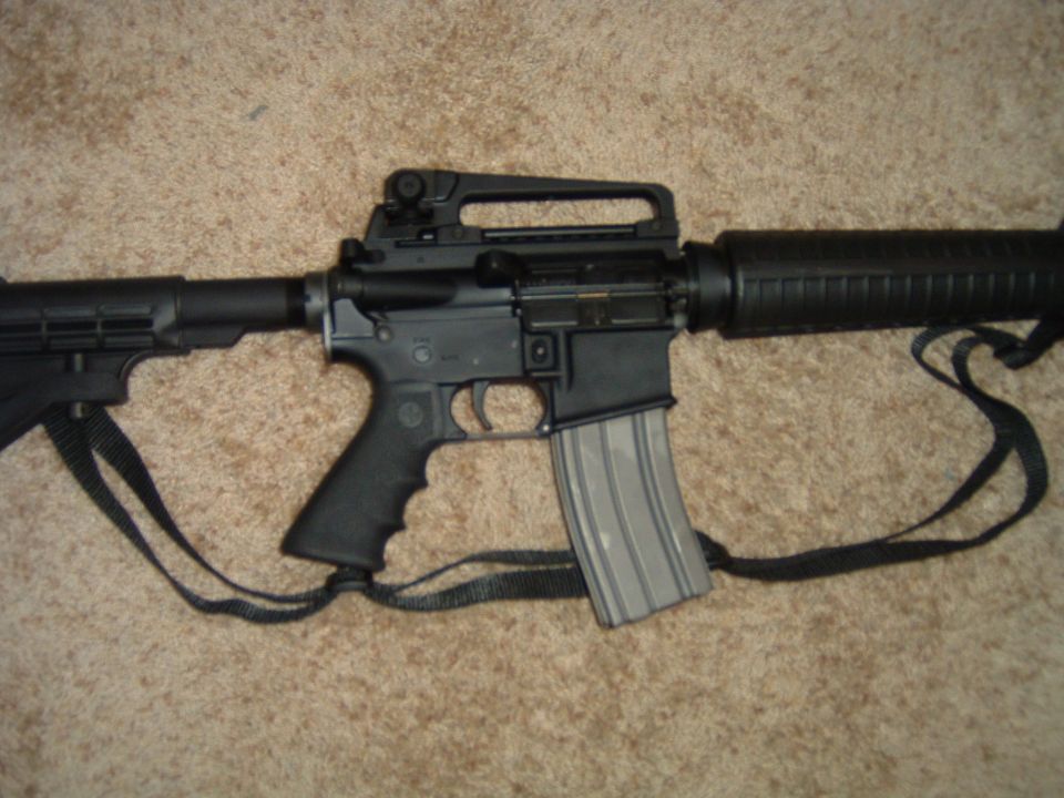AR-15 style rifle with a magazine inserted, resting on carpet