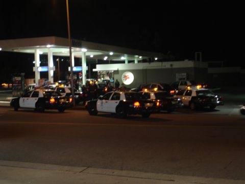 1993 Ford Taurus - Multiple police vehicles are gathered at a gas station under the lights.