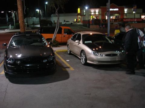 1993 Ford Taurus - Two Ford Tauruses are parked in a lot at night, with a McDonald's in the background.