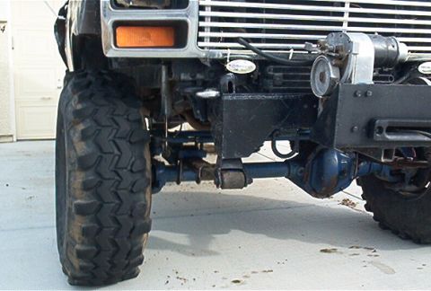 1986 Ford Bronco - Close-up view of the front axle, leaf springs, and tire of a heavy-duty truck.