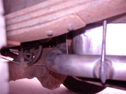 1990 Ford Bronco - Close-up view of the undercarriage of a vehicle, revealing suspension and exhaust system components.