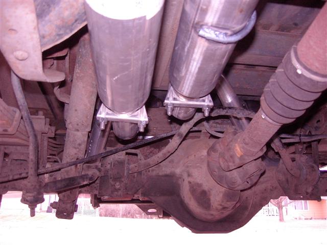 Underside view of a vehicle's rear axle and dual exhaust pipes with custom hangers