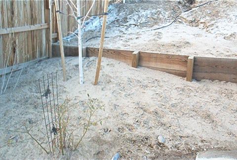 1986 Ford Bronco - A backyard scene shows construction elements including a wooden retaining wall and sandy ground.