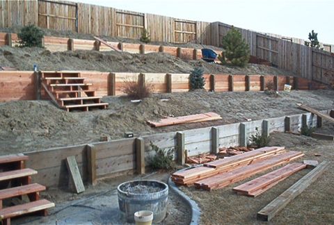 1986 Ford Bronco - A backyard scene shows construction of tiered retaining walls and wooden stairs with lumber piled nearby.
