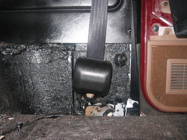 Seatbelt anchor and black textured flooring in a vehicle interior
