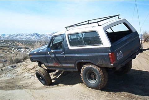 1986 Ford Bronco - Ford Bronco navigates a steep, sandy incline with mountains in the background.
