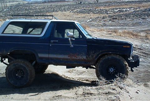 1986 Ford Bronco - This lifted Ford Bronco is navigating a sandy, off-road environment.