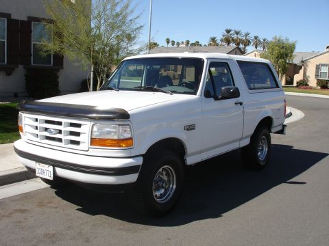 1996 Ford Bronco - This white 1996 Ford Bronco is parked in front of a house on a sunny day.
