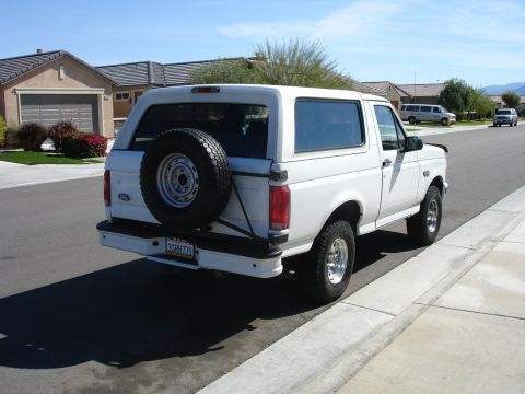 1996 Ford Bronco - This white Ford Bronco is parked curbside in a residential neighborhood on a sunny day.