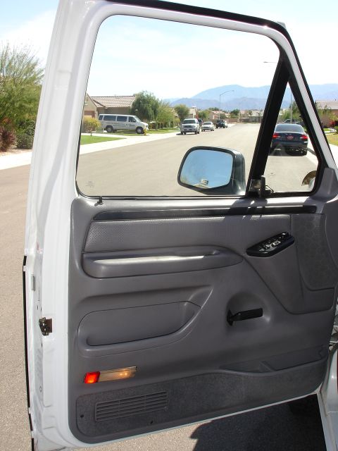 1996 Ford Bronco - View from inside a white truck, looking out at a street with houses and other cars.