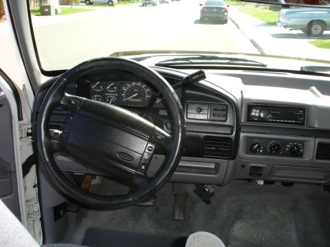 1996 Ford Bronco - The interior of a truck shows the dashboard, steering wheel, and a view of the road ahead with other vehicles.