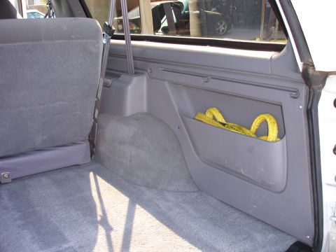 1996 Ford Bronco - Rear interior cargo area of a 1996 Ford Bronco, a storage pocket and a yellow tow strap.