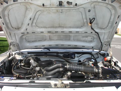 1996 Ford Bronco - The engine compartment of a white truck is shown with the hood fully open, revealing the engine and various components.