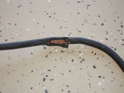 1996 Ford Bronco - A damaged wire with exposed copper is shown against a speckled garage floor background.