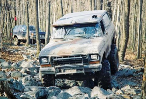 1979 Ford Bronco - Two Ford Broncos navigating a rocky trail in a wooded area.