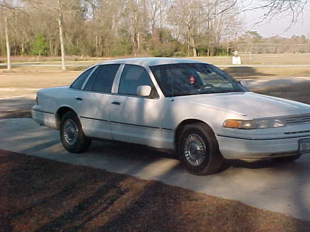 White sedan parked on concrete, side and front visible. Chrome wheels, clear headlights