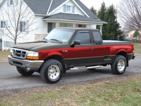 1997 Ford Probe - A two-tone black and red Ford Ranger pickup truck is parked in front of a house.