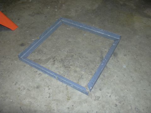 1991 Ford Bronco - Metal frame part on concrete floor, with an orange object in the background.